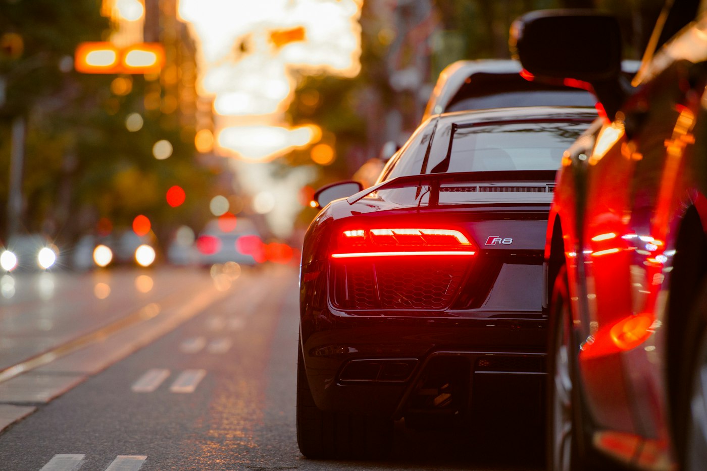 Dark sports car with its rear lamps lit at dusk